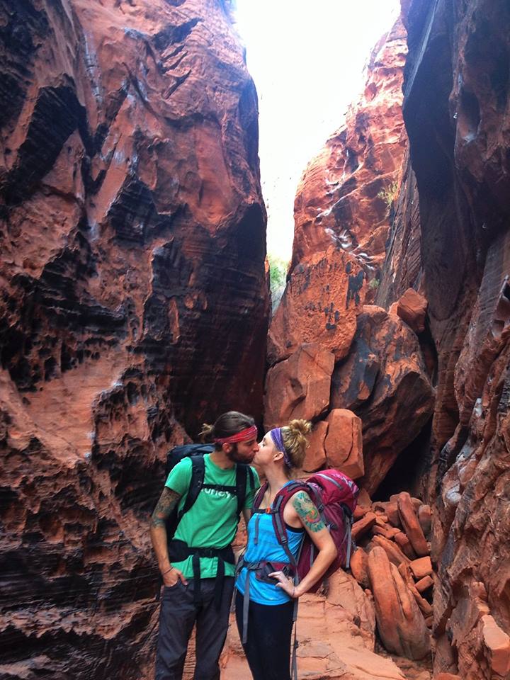 A couple kissing in front of a rock formation who found love while rock climbing.