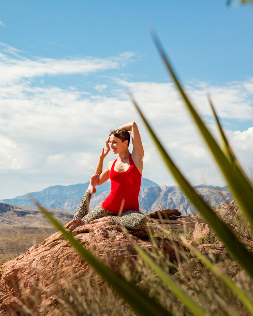 Woman rock climber practicing yoga stretch outside.