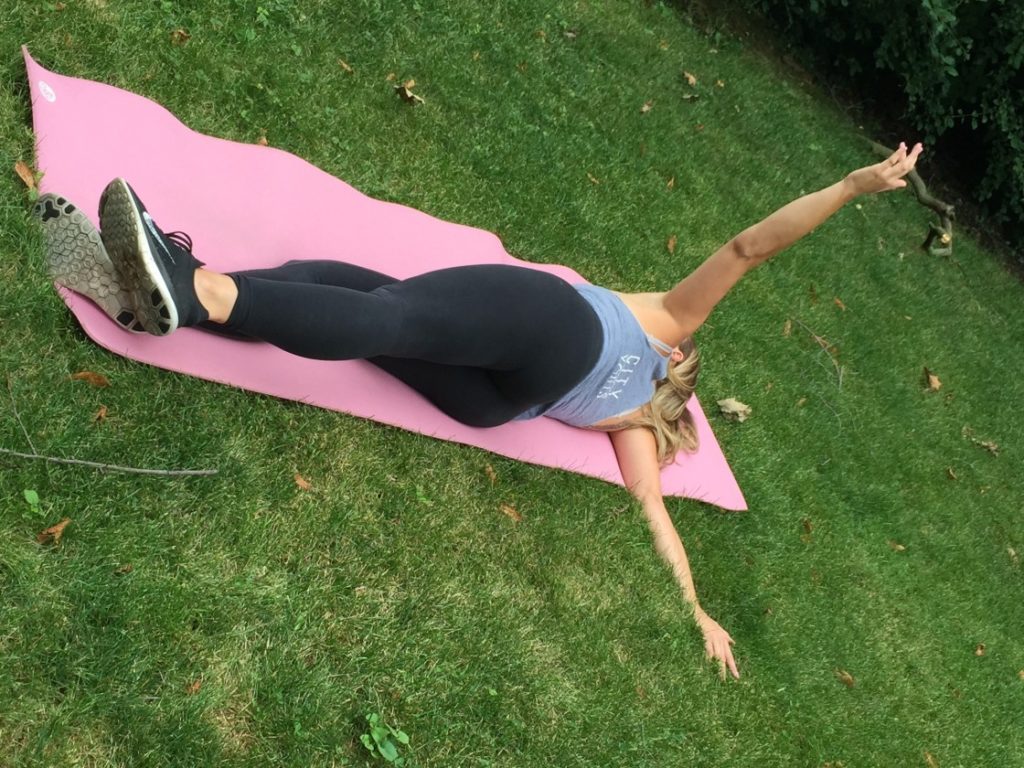 Woman lying on yoga mat with arms stretched.
