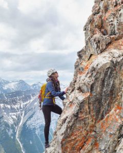 Woman climbing the side of a mountain.