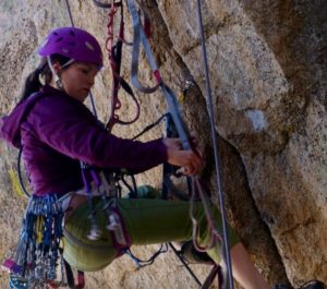 Woman using climbing gear to aid climbing.