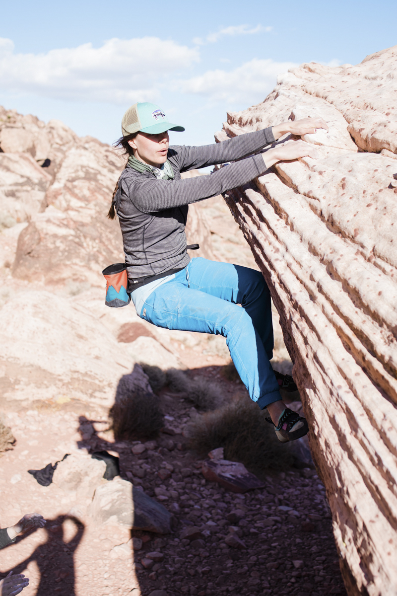 Woman gripping onto the side of a rock while climbing.