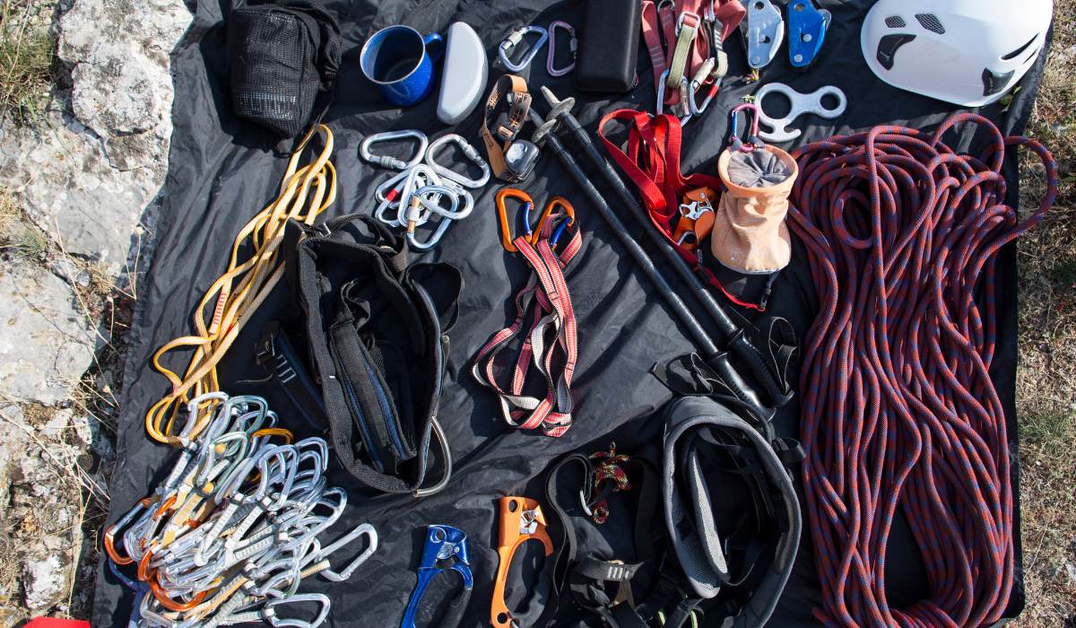 Assortment of rock climbing gear, or rack, like rope, chalk, helmet and caribiners.