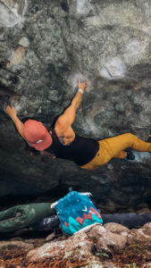 woman rock climbing in yellow rock climbing pants and red hat