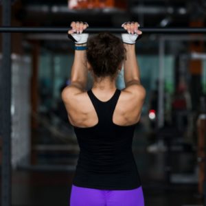 Woman doing a pull up to increase strength for rock climbing.