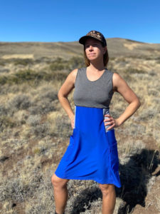 A woman wearing a sport skirt stands outside with her hands on her hips.